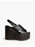 Sandalia con cuña. Corte cruzado. Cierre mediante hebilla en el lateral. Cuña en efecto madera. Detalle de tachas. Altura del ta
